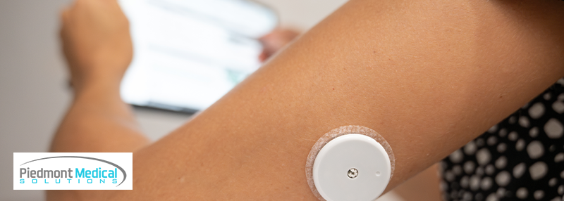 Woman's arm with a CGM sensor attached to the back of it