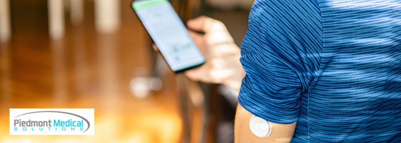Man with CGM device on his arm and using his smartphone to check blood sugar levels