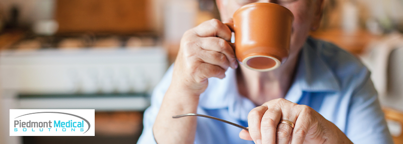 Older woman sitting at the table and drinking out of a coffee mug