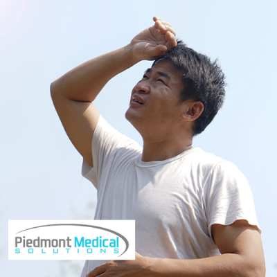 Asian man holding his hand to his head looking up at the sky outside.