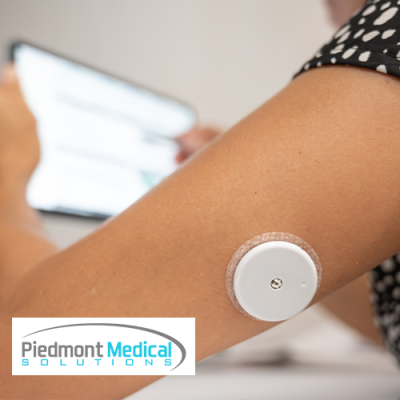 Woman's arm with a CGM sensor attached to the back of it
