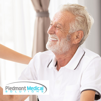 Nurse and male patient smiling at each other while nurse holds his hand