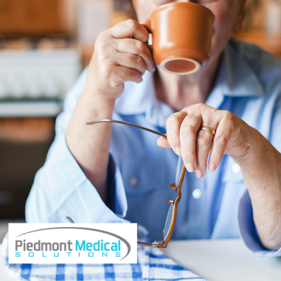 Older woman sitting at the table and drinking out of a coffee mug